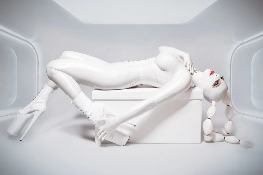 Model in futuristischem, wei&szlig;en Latexanzug mit Maske und Plateau-High-Heels bei kunstvollem Fetish-Shooting von Catherine Cayden
